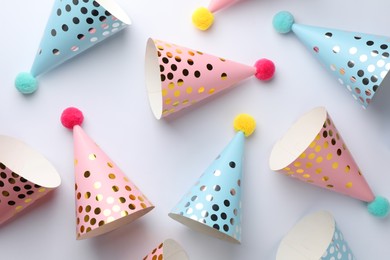 Photo of Colorful party hats with pompoms on light background, top view