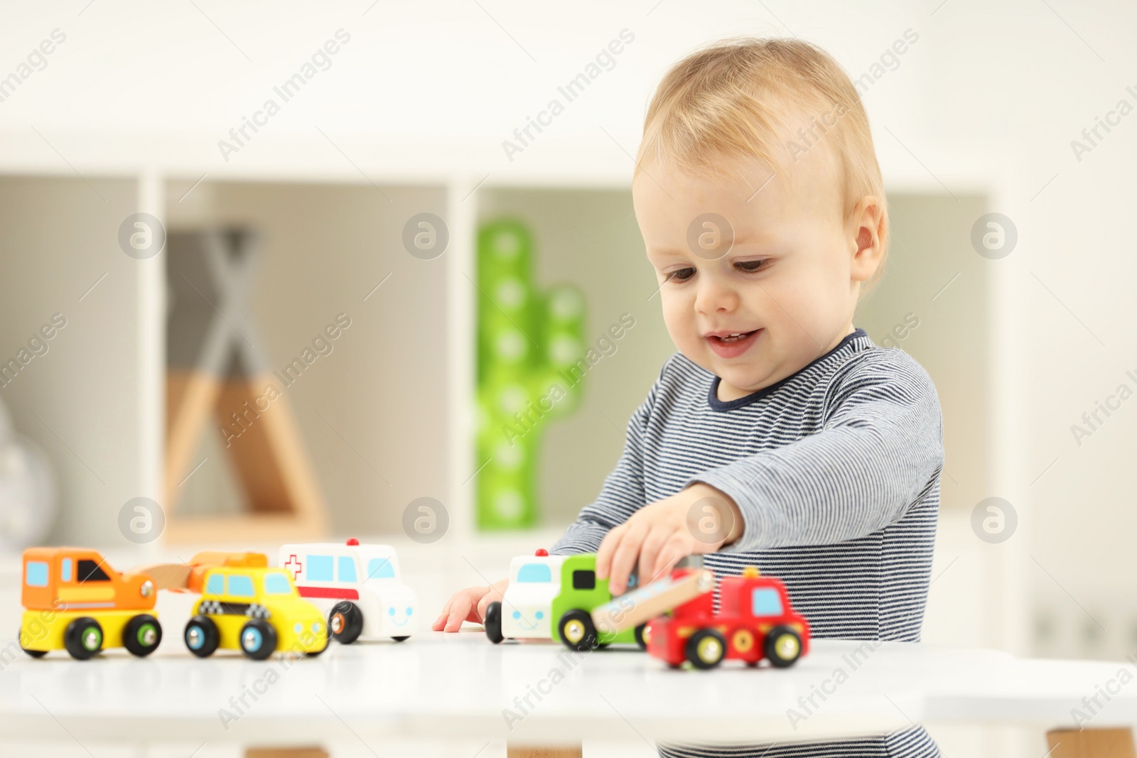 Photo of Children toys. Cute little boy playing with toy cars at white table in room, space for text