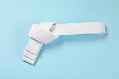 Photo of White karate belt on light blue background, top view