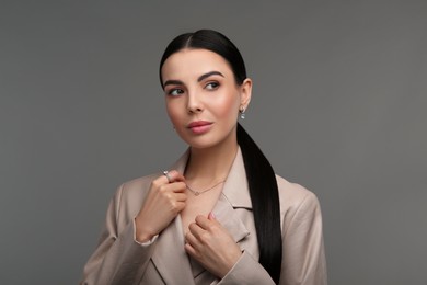 Photo of Beautiful young woman with elegant jewelry on dark grey background