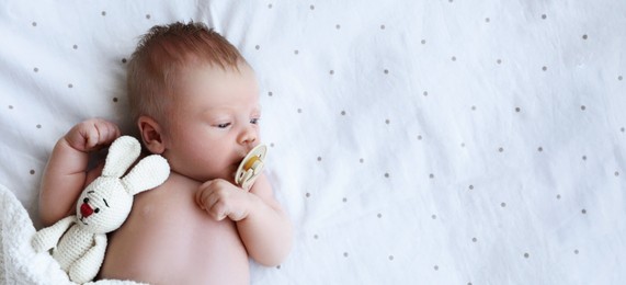 Image of Cute newborn baby with toy lying in bed, top view with space for text. Banner design