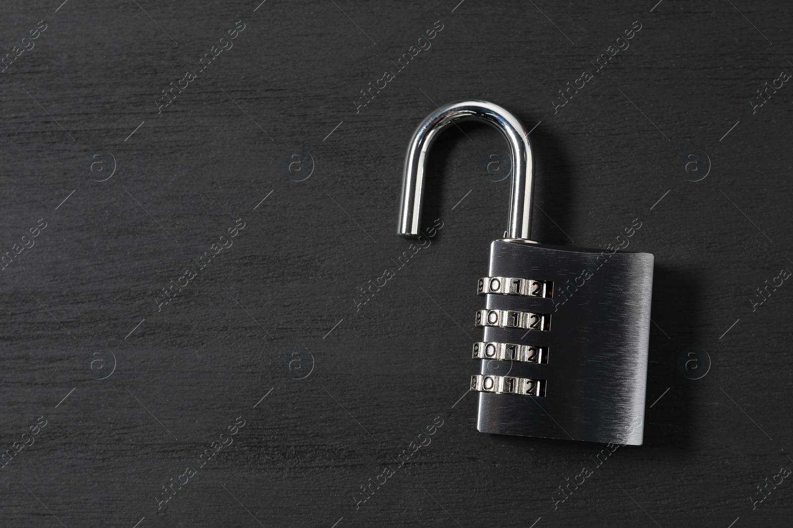 Photo of One steel combination padlock on black wooden table, top view. Space for text