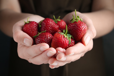 Photo of Woman holding many tasty fresh strawberries, closeup