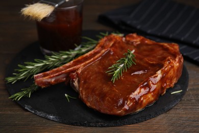 Tasty marinated meat and rosemary on wooden table, closeup