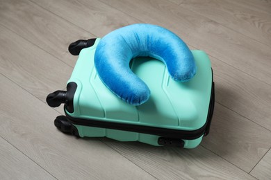 Photo of Turquoise travel pillow and suitcase on floor