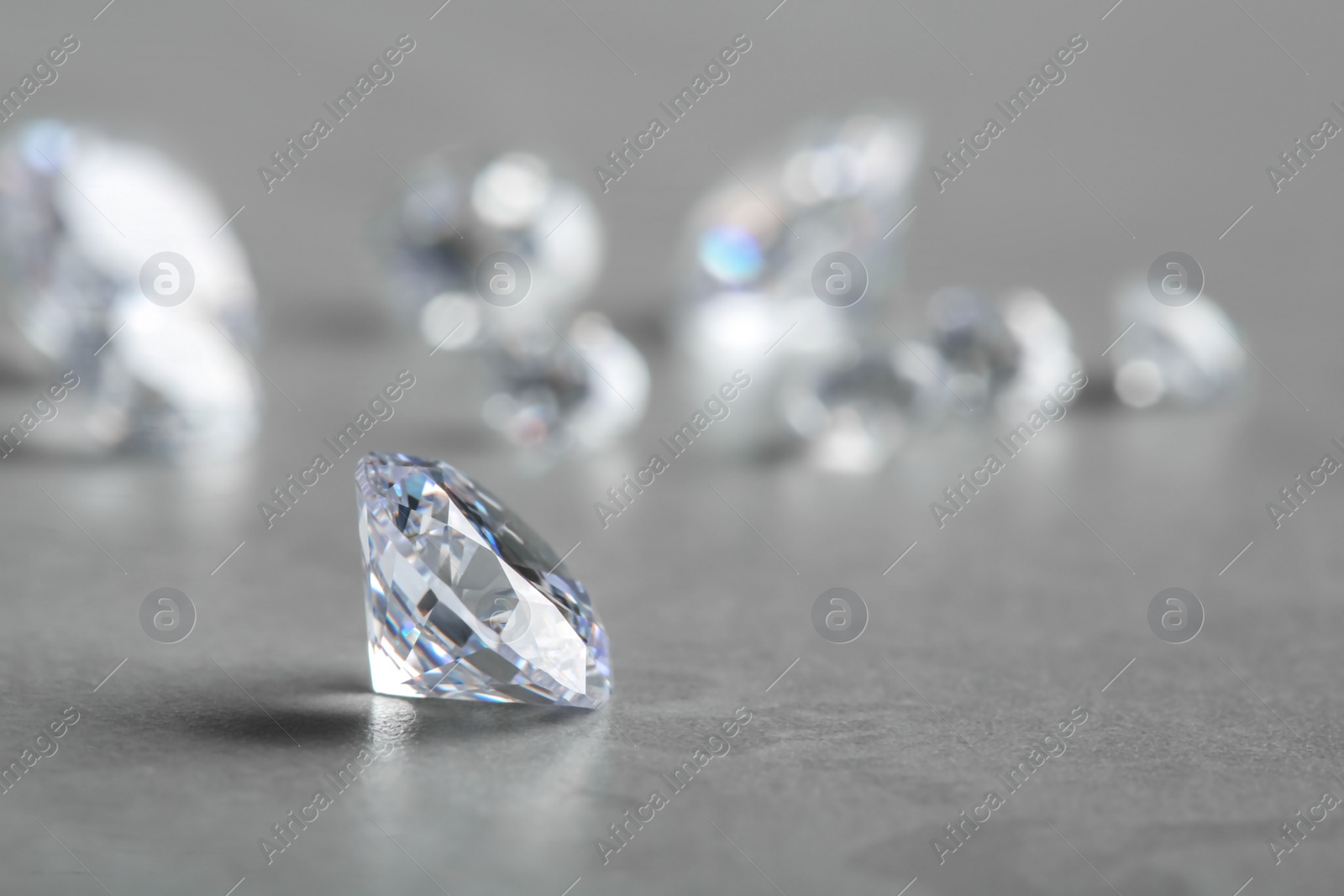 Photo of Beautiful shiny diamond on gray table, space for text