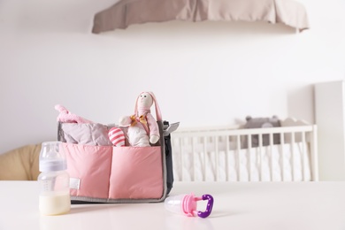 Maternity bag with baby accessories on table indoors. Space for text