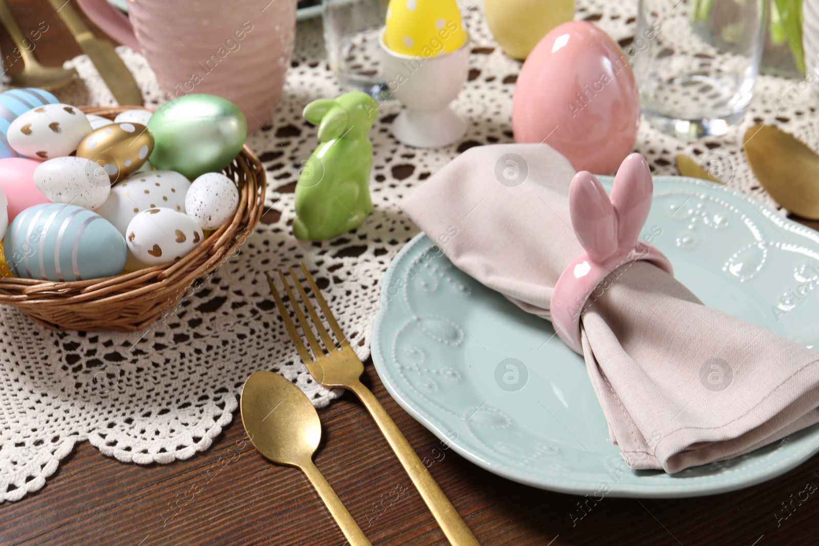 Photo of Festive table setting with napkin ring in shape of bunny ears, closeup. Easter celebration