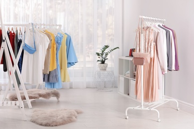 Racks with stylish clothes in light room