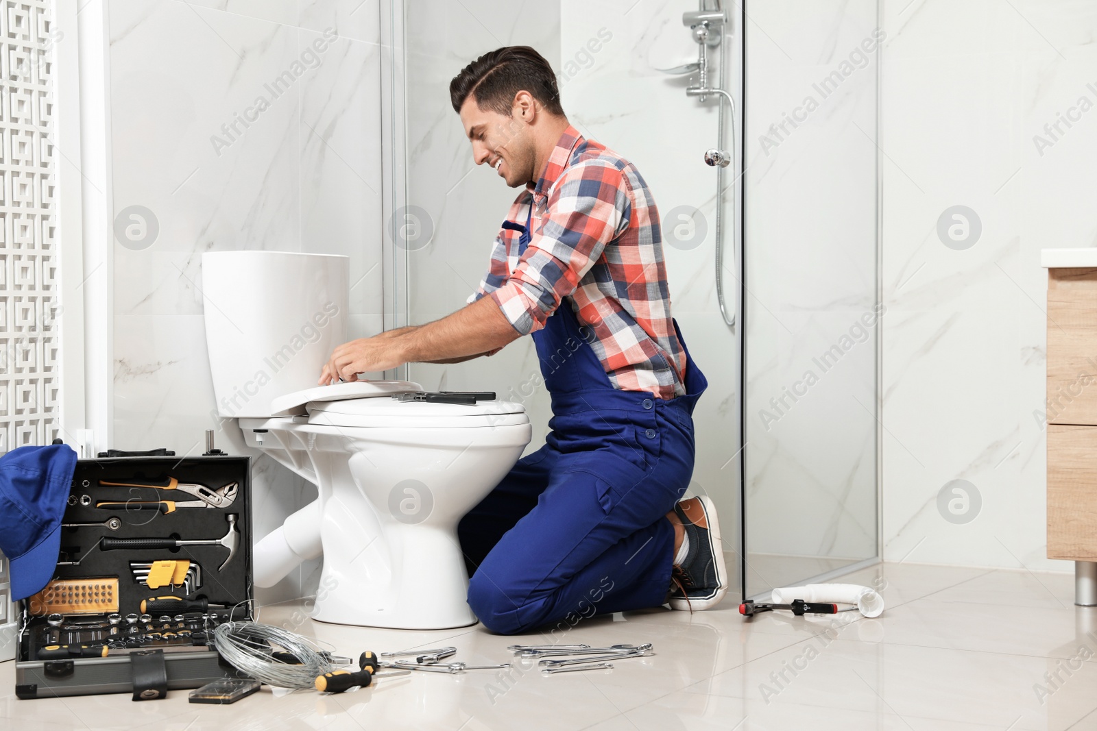 Photo of Professional plumber working with toilet bowl in bathroom