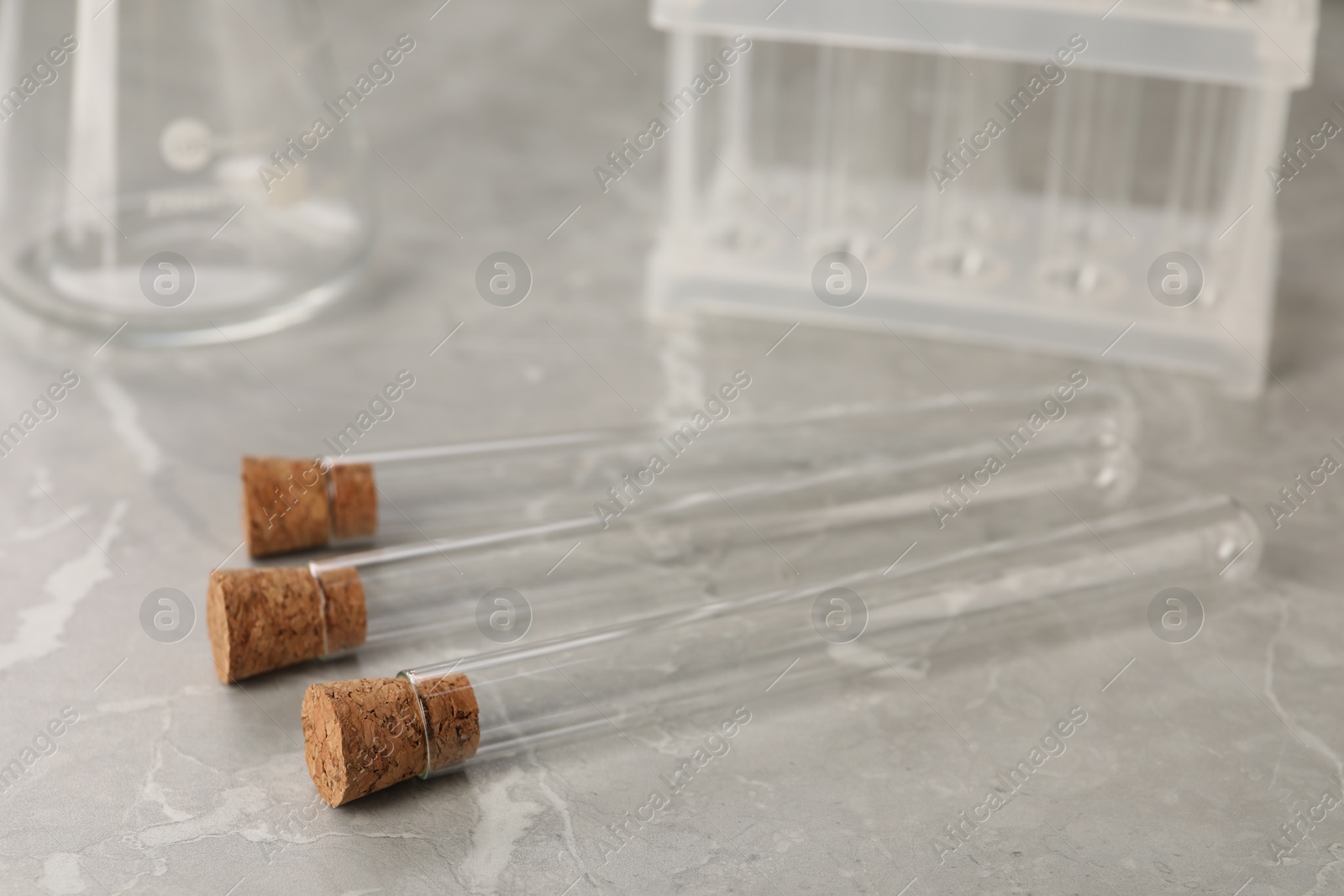 Photo of Test tubes on grey marble table, closeup. Laboratory glassware