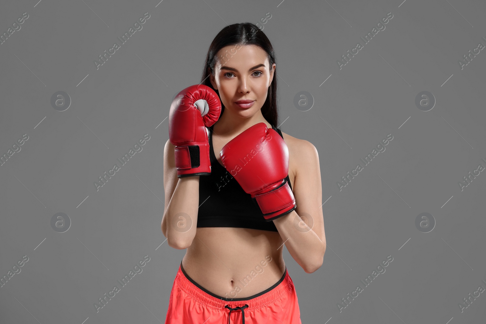 Photo of Portrait of beautiful woman in boxing gloves on grey background