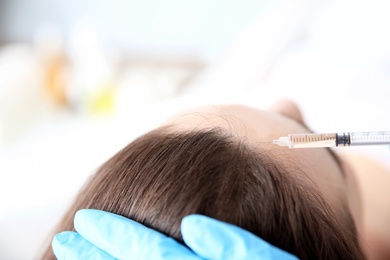 Young woman with hair loss problem receiving injection in clinic