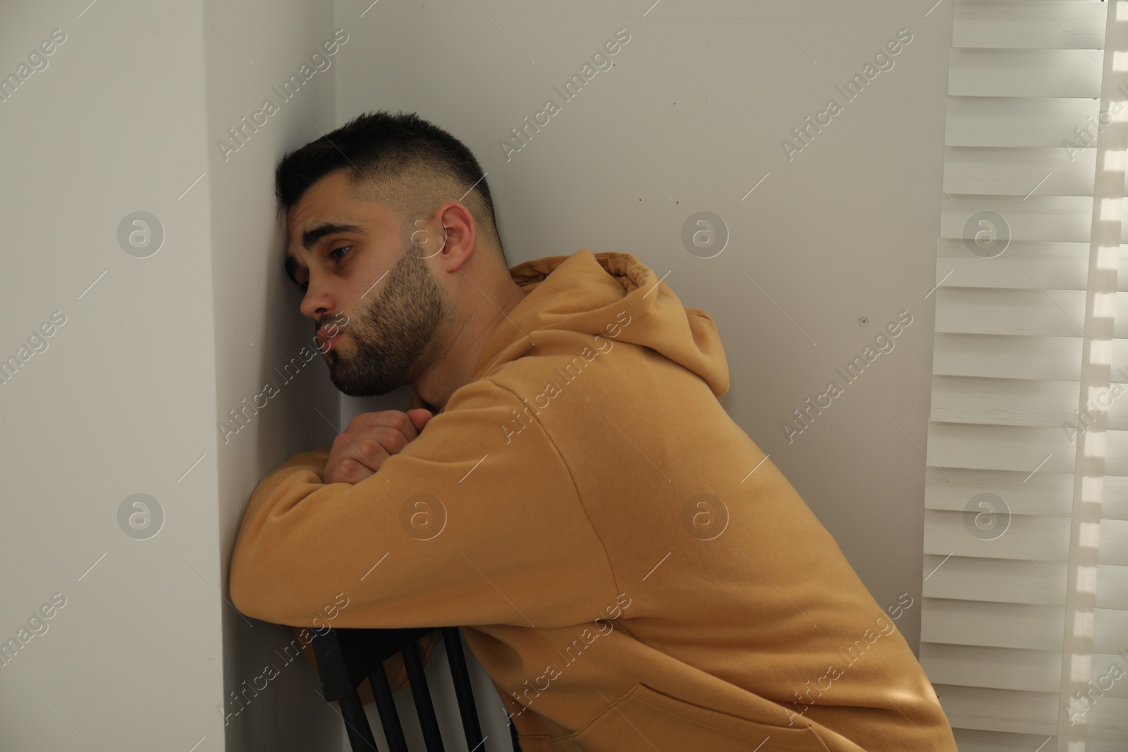 Photo of Sad young man in hoodie at home