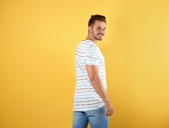 Young man in stylish jeans on color background