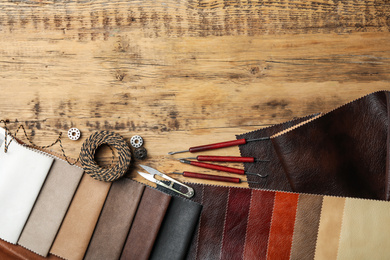 Photo of Flat lay composition with leather samples and tools on  wooden table. Space for text