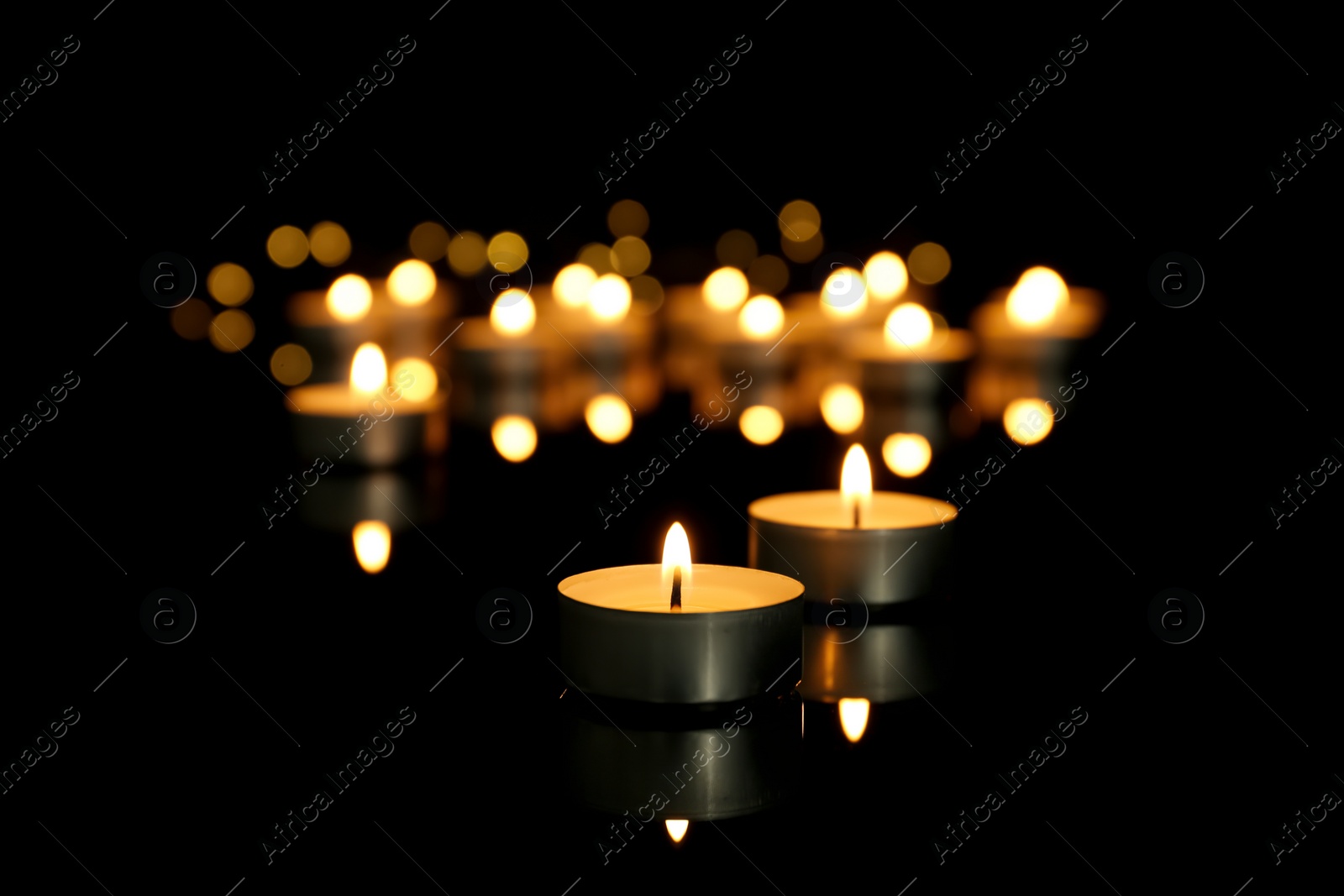 Photo of Burning candles on table against dark background