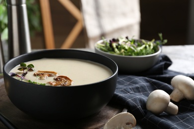 Photo of Delicious cream soup with mushrooms on table