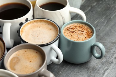 Many cups of different coffees on slate table, closeup