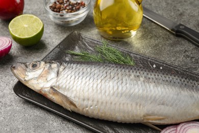 Photo of Delicious salted herring and ingredients on grey table, closeup