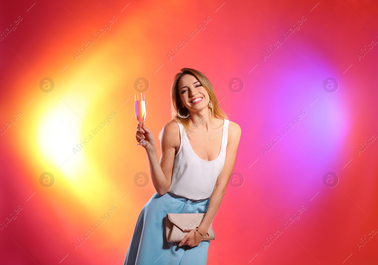 Photo of Portrait of happy woman with champagne in glass and handbag on color background