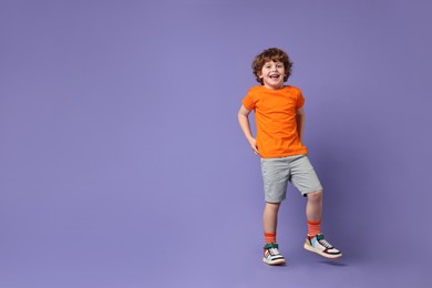 Happy little boy dancing on violet background. Space for text