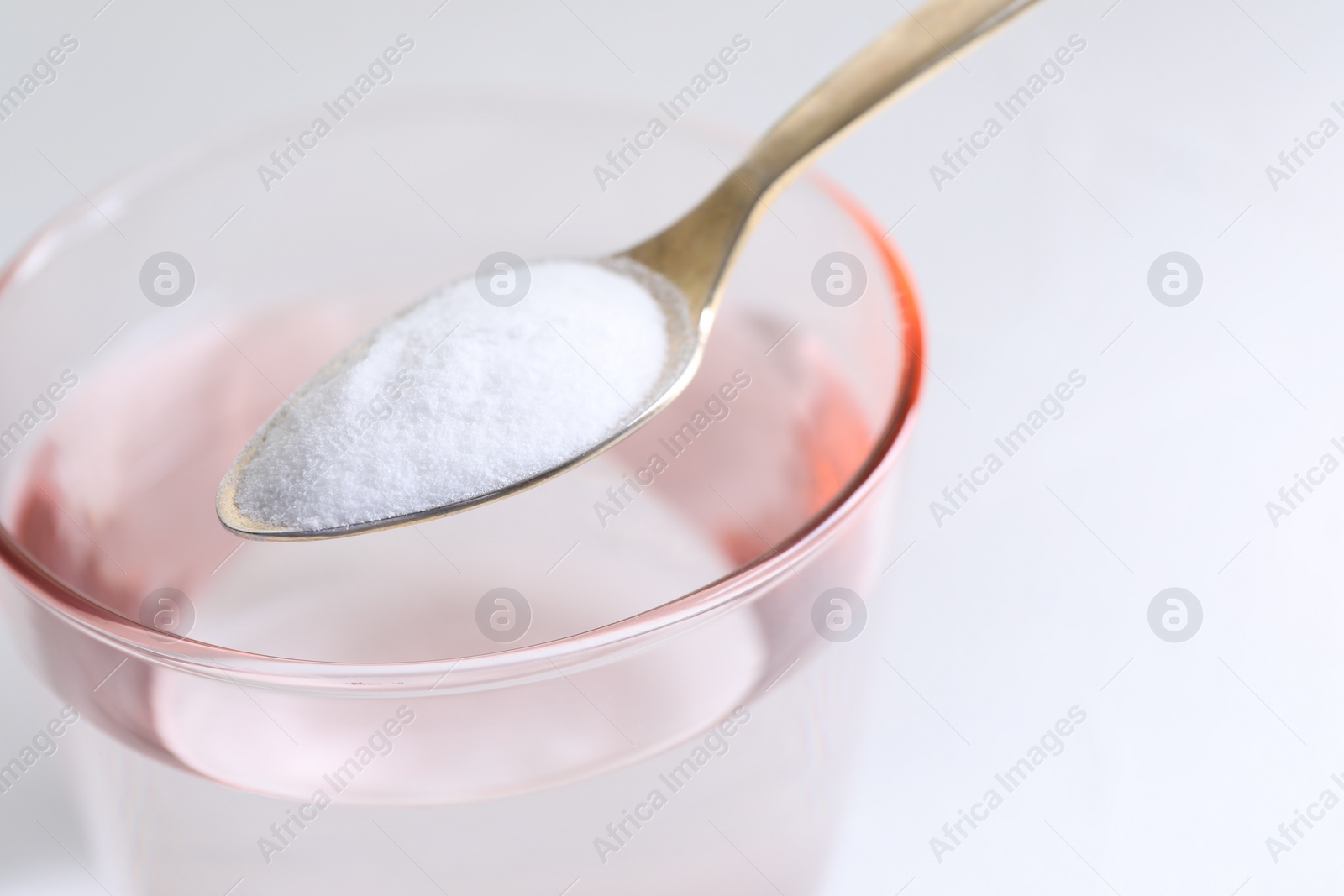 Photo of Spoon with baking soda over glass of water on white background, closeup. Space for text