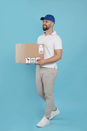 Photo of Courier holding cardboard box on light blue background
