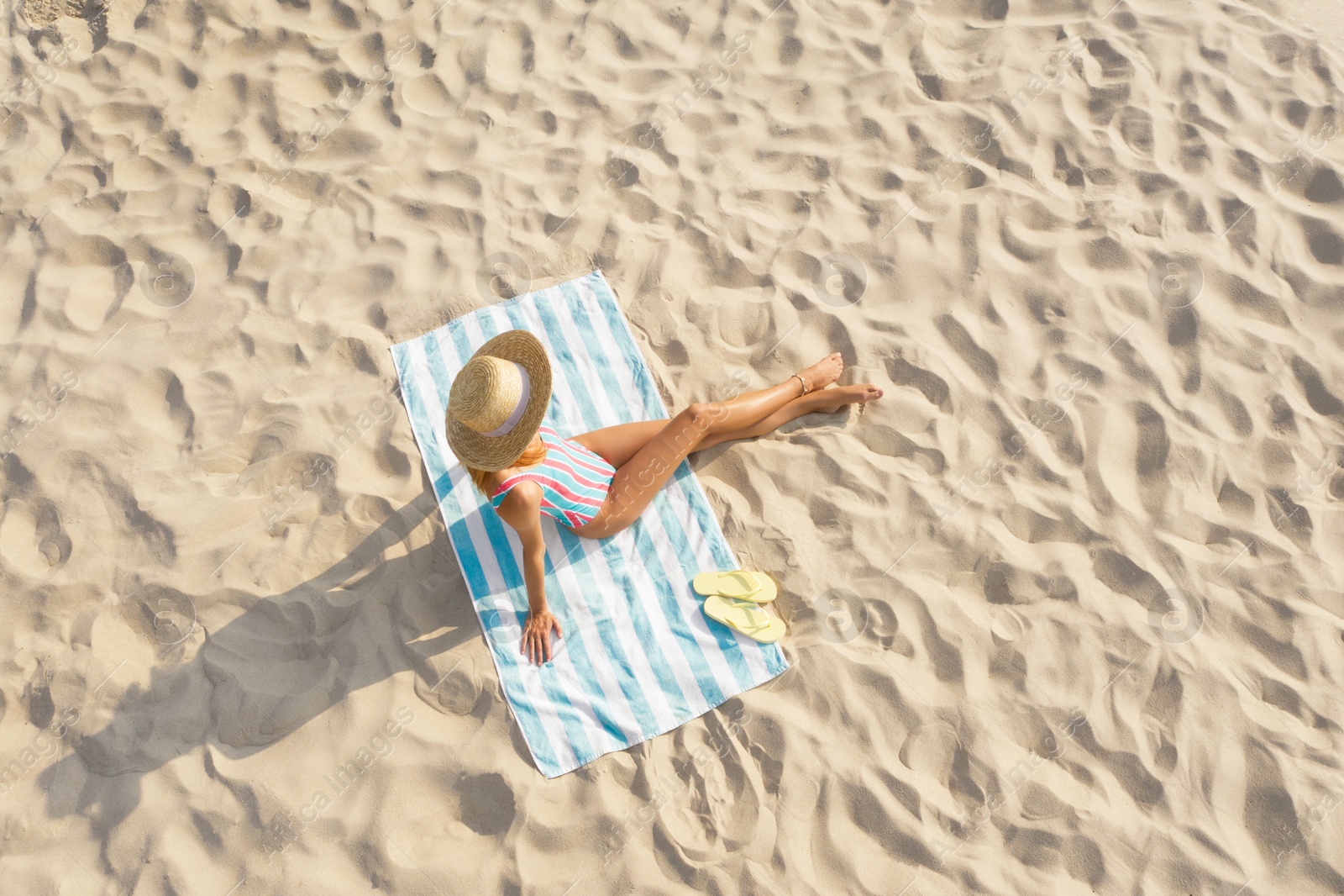 Image of Woman sunbathing on beach towel at sandy coast, aerial view