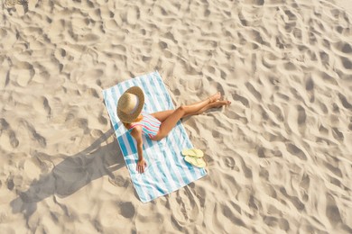 Woman sunbathing on beach towel at sandy coast, aerial view