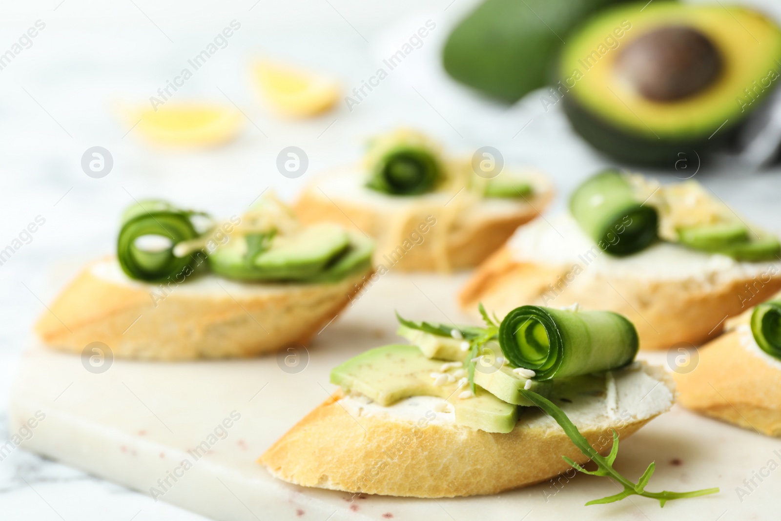 Photo of Delicious sandwiches with cucumber and avocado on white table