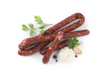 Photo of Thin dry smoked sausages and different spices isolated on white, top view