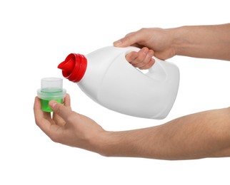 Photo of Man pouring fabric softener from bottle into cap for washing clothes on white background, closeup