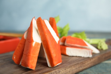 Photo of Fresh crab sticks served on wooden board, closeup