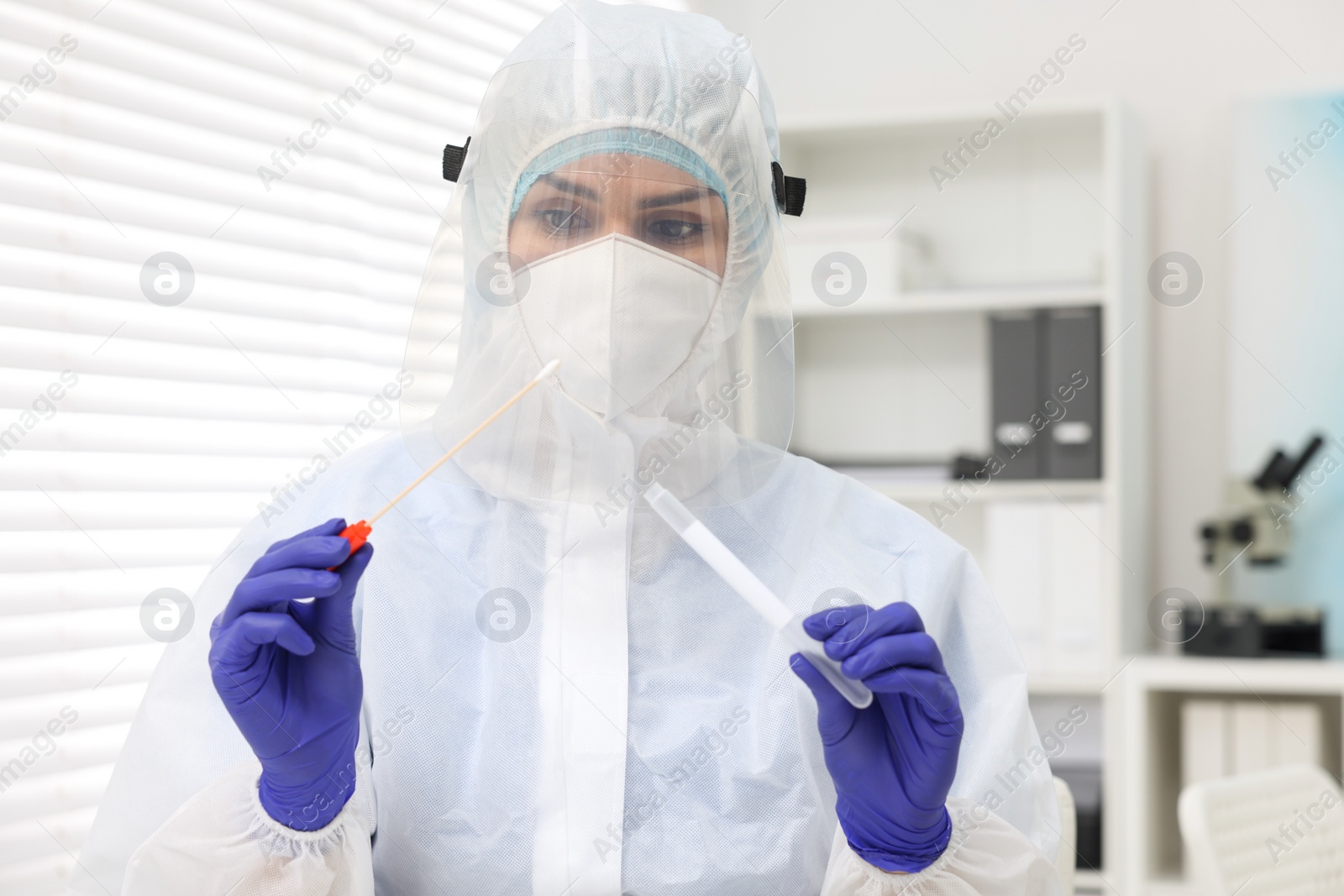Photo of Laboratory testing. Doctor in uniform with cotton swab and tube at hospital