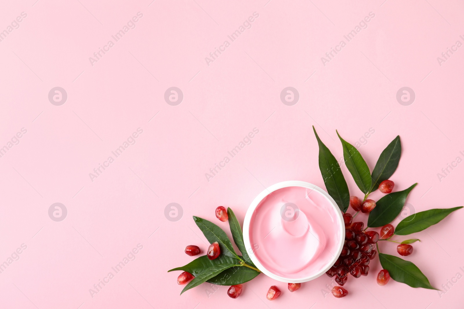 Photo of Fresh pomegranate and jar of facial mask on pink background, flat lay. Space for text