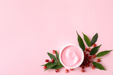 Fresh pomegranate and jar of facial mask on pink background, flat lay. Space for text