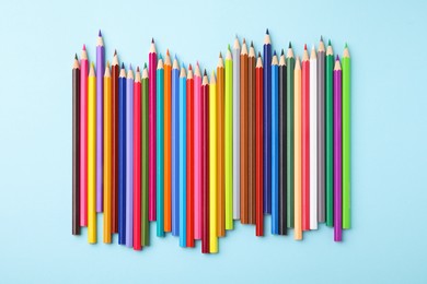 Colorful wooden pencils on light blue background, flat lay