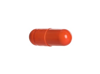 Photo of One orange pill on white background. Medicinal treatment