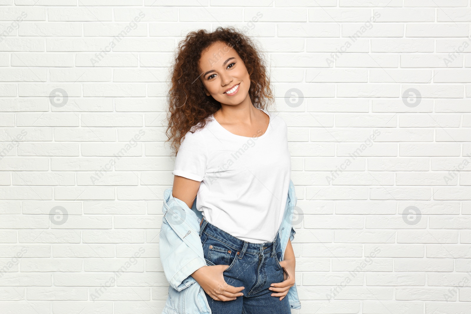 Photo of Young African-American woman with beautiful face near white brick wall