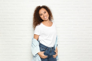 Young African-American woman with beautiful face near white brick wall