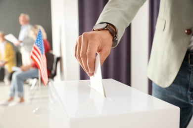 Photo of Man putting ballot paper into box at polling station, closeup