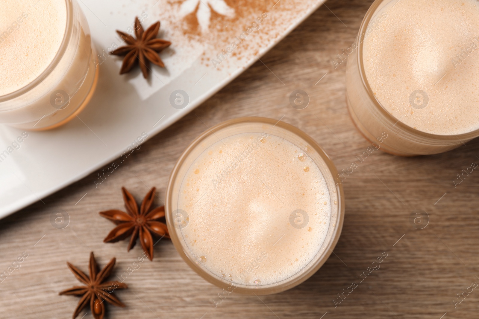 Photo of Delicious eggnog with anise on wooden table, flat lay