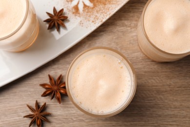 Delicious eggnog with anise on wooden table, flat lay