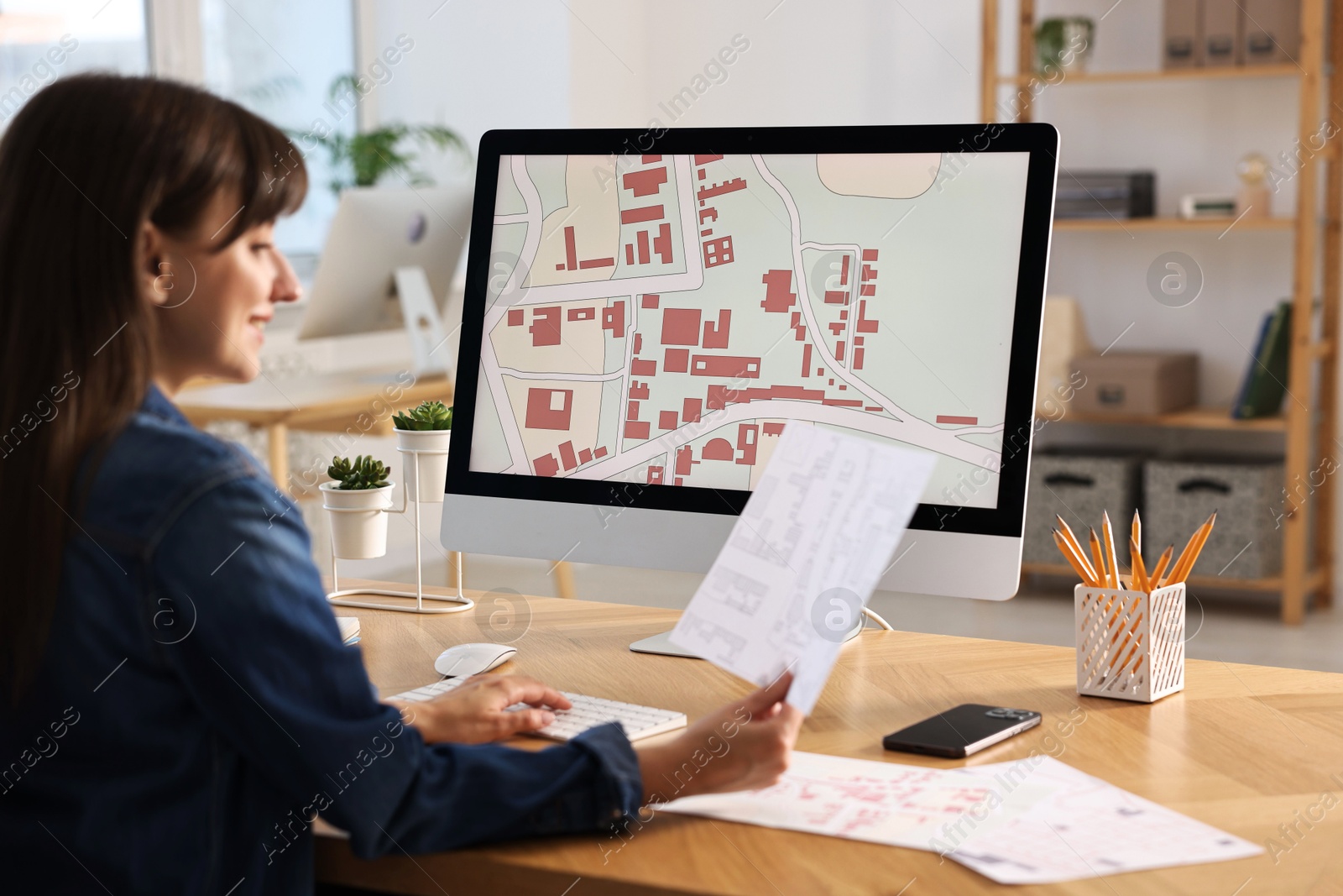 Photo of Cartographer working with cadastral maps at table in office