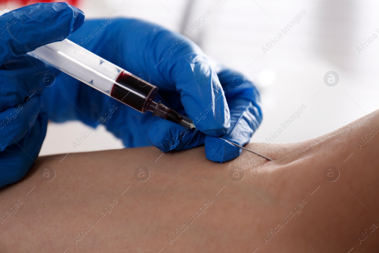 Photo of Nurse drawing blood sample from patient in clinic, closeup