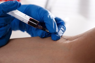 Nurse drawing blood sample from patient in clinic, closeup