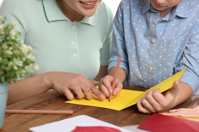 Little girl with her mother making beautiful greeting card at home, closeup