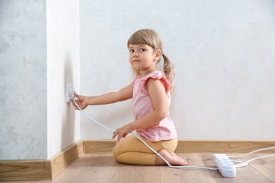 Little child playing with electrical socket and power strip plug at home. Dangerous situation