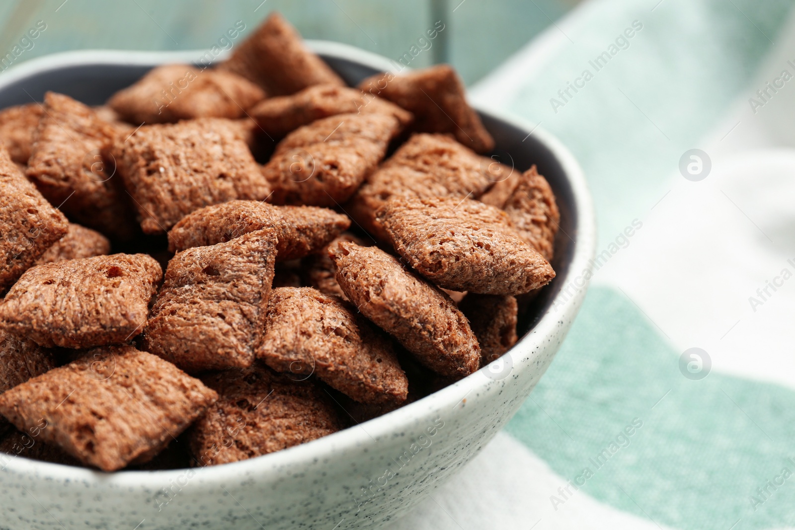 Photo of Bowl of sweet crispy corn pads on kitchen towel, closeup. Breakfast cereal